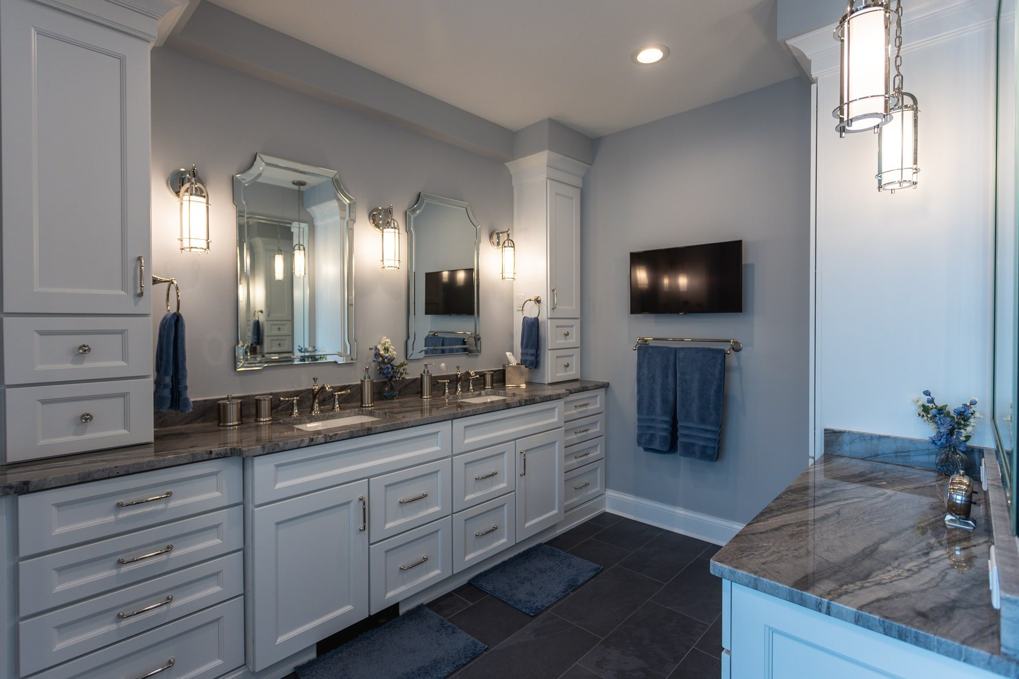 Spacious bathroom with double vanity, wall-mounted TV, and sconce lighting by Legacy Builders Group in Greater Cincinnati
