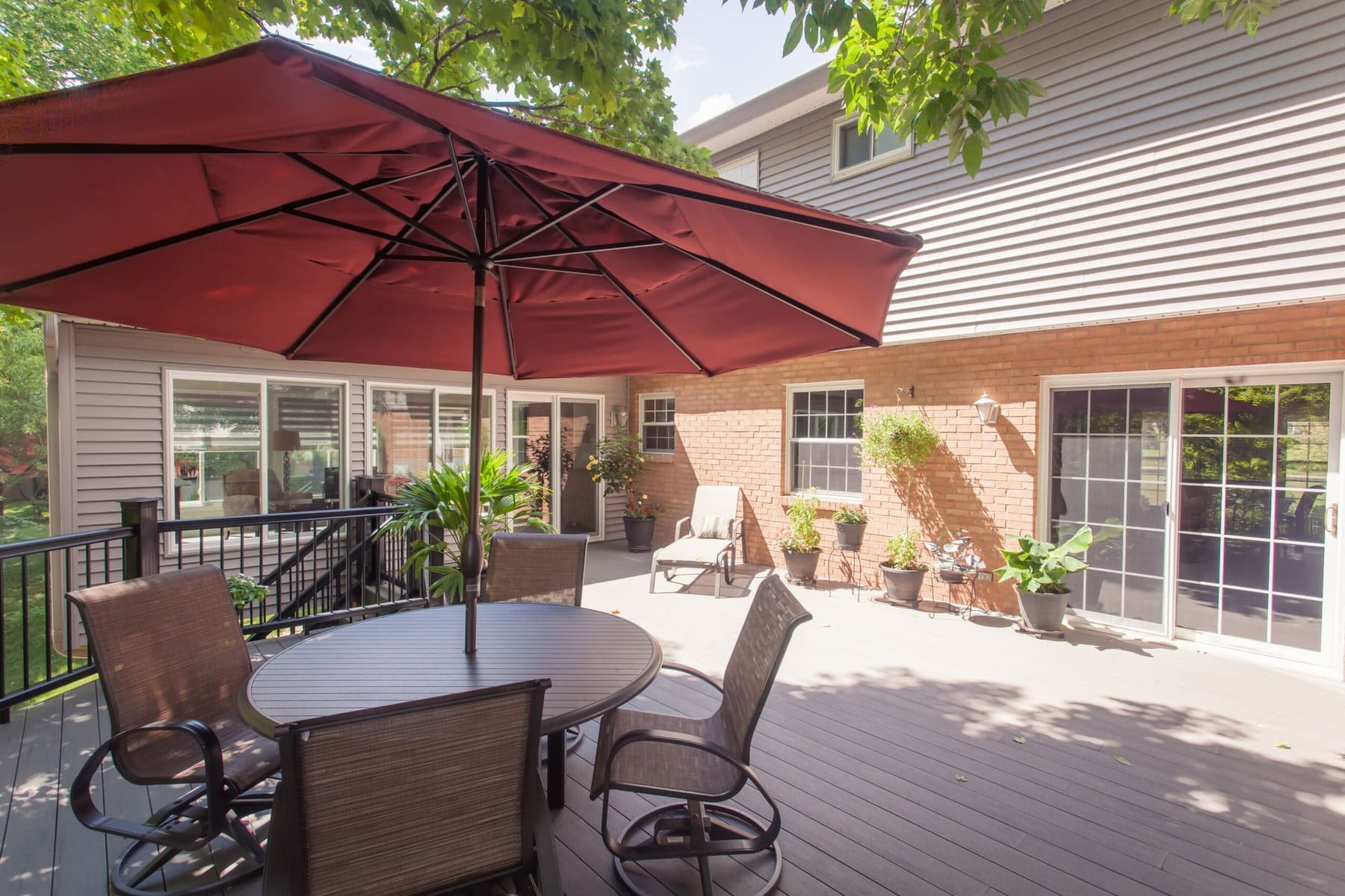 Spacious outdoor deck with dining area, umbrella, and access to a sunroom addition in Madeira, OH