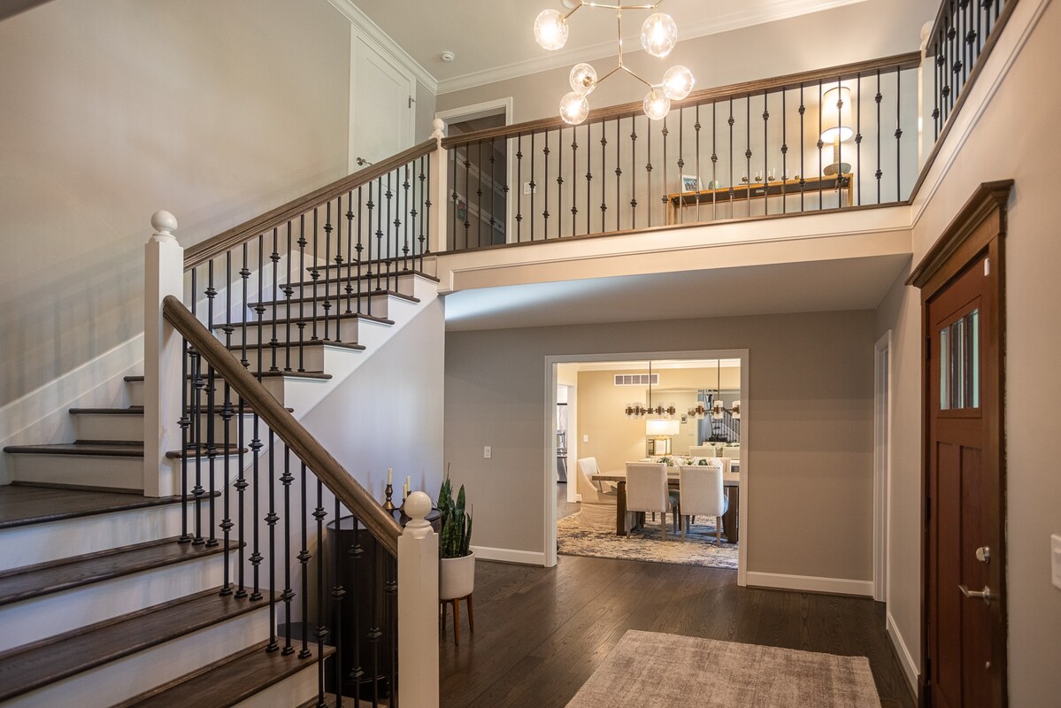 Staircase in foyer of Cincinnati home remodel with modern glass chandelier above main floor