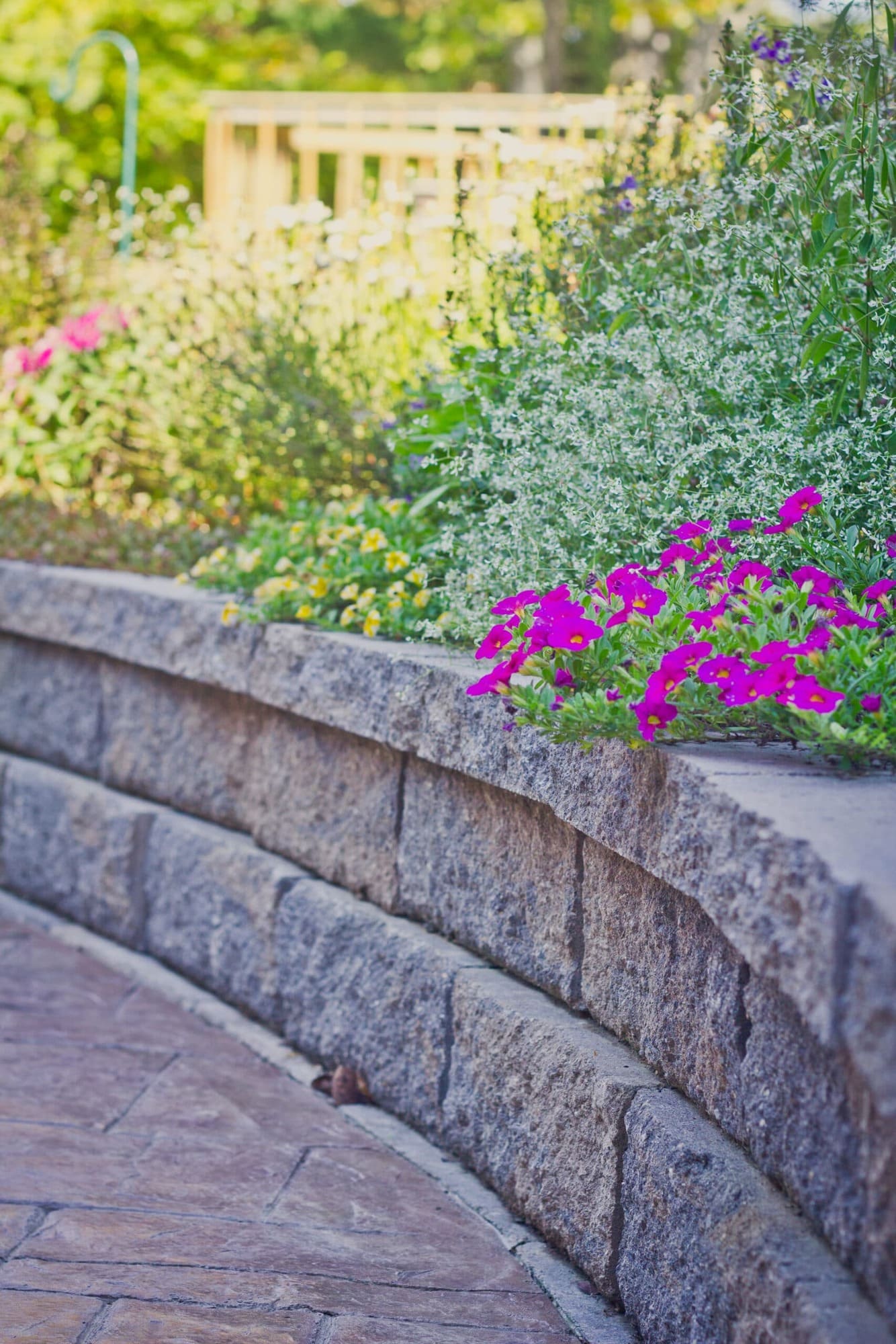 Stone retaining wall with colorful flowers and patio walkway by Legacy Builders Group in Greater Cincinnati