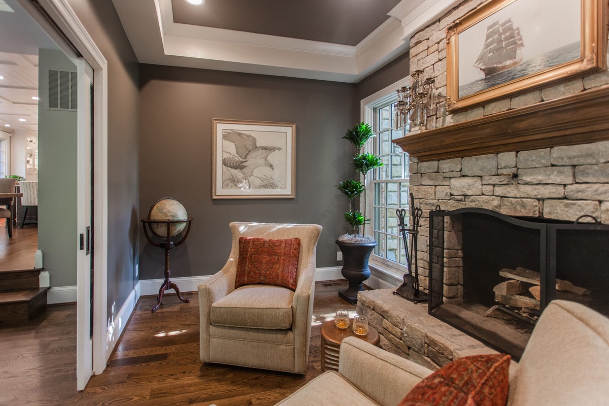 Two chairs in home addition with tray ceiling above and stacked stone fireplace mantle 