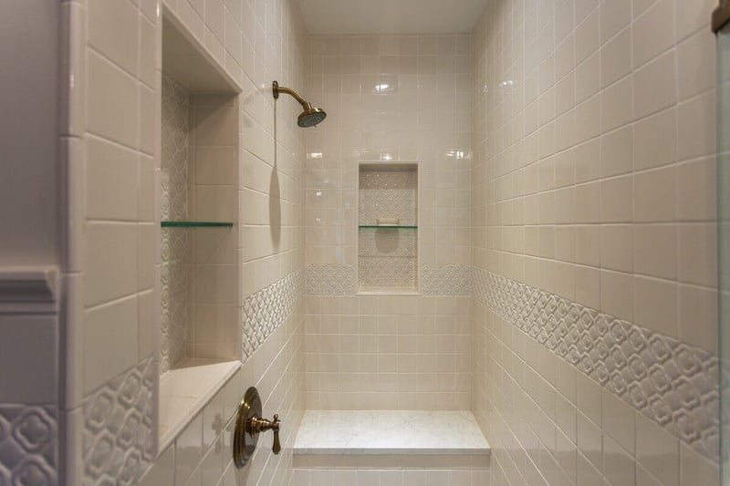 Walk-in shower with built-in bench and shelf in historic bathroom renovation in Wyoming, Ohio by Legacy Builders