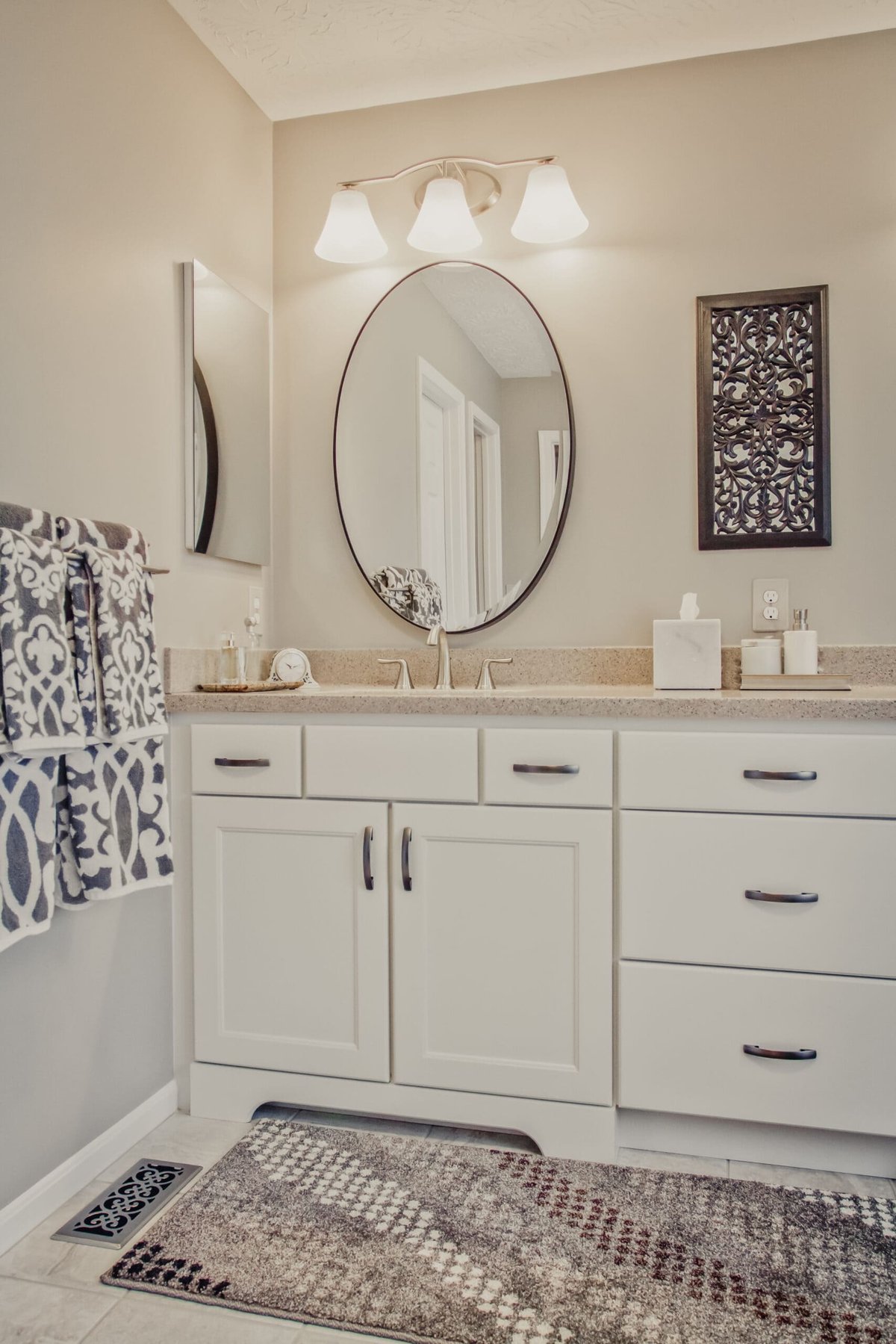 White bathroom vanity with three light sconces above mirror in Legacy Builders remodel