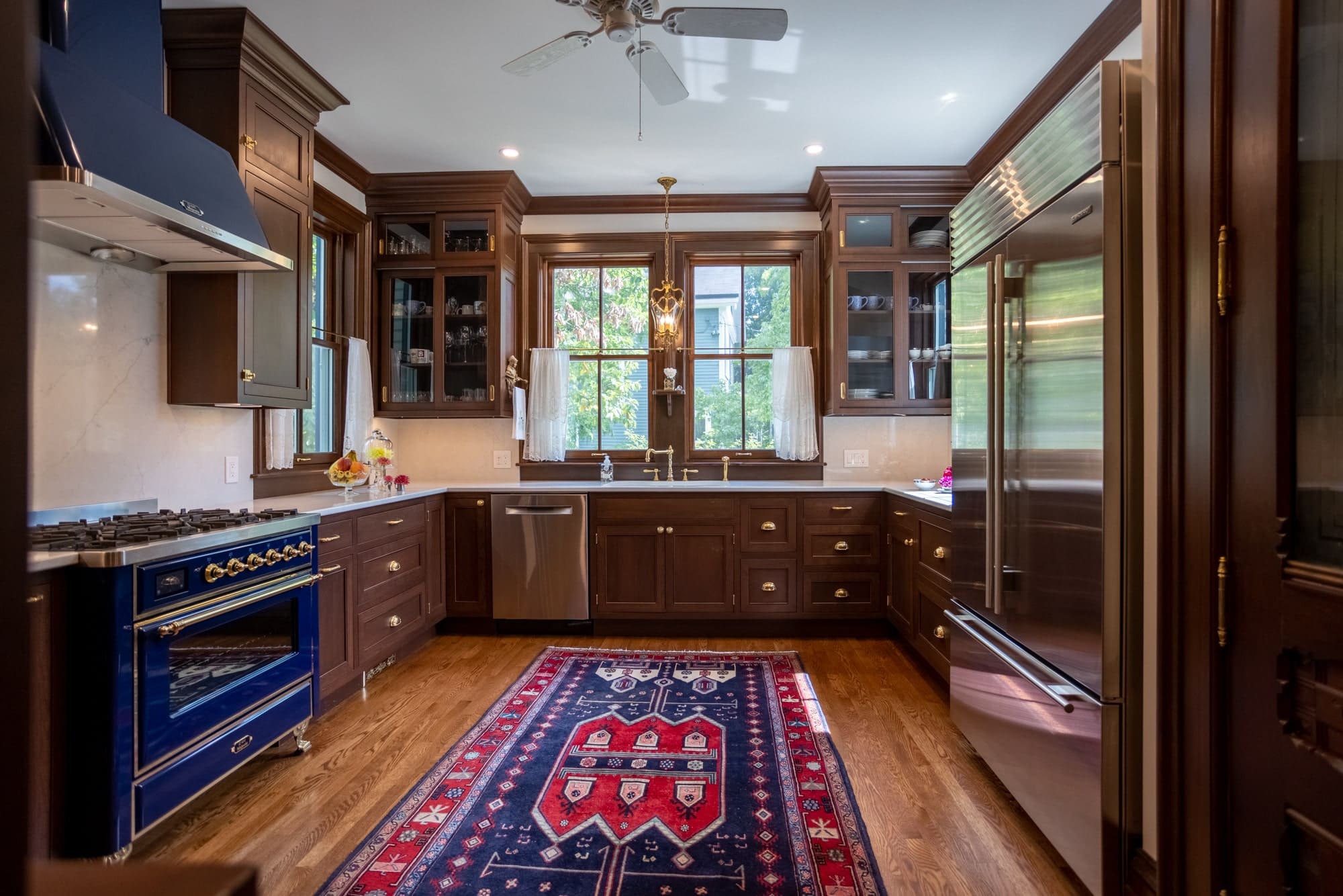 Wide view of a Greater Cincinnati kitchen with rich wood cabinetry, blue range and patterned runner rug