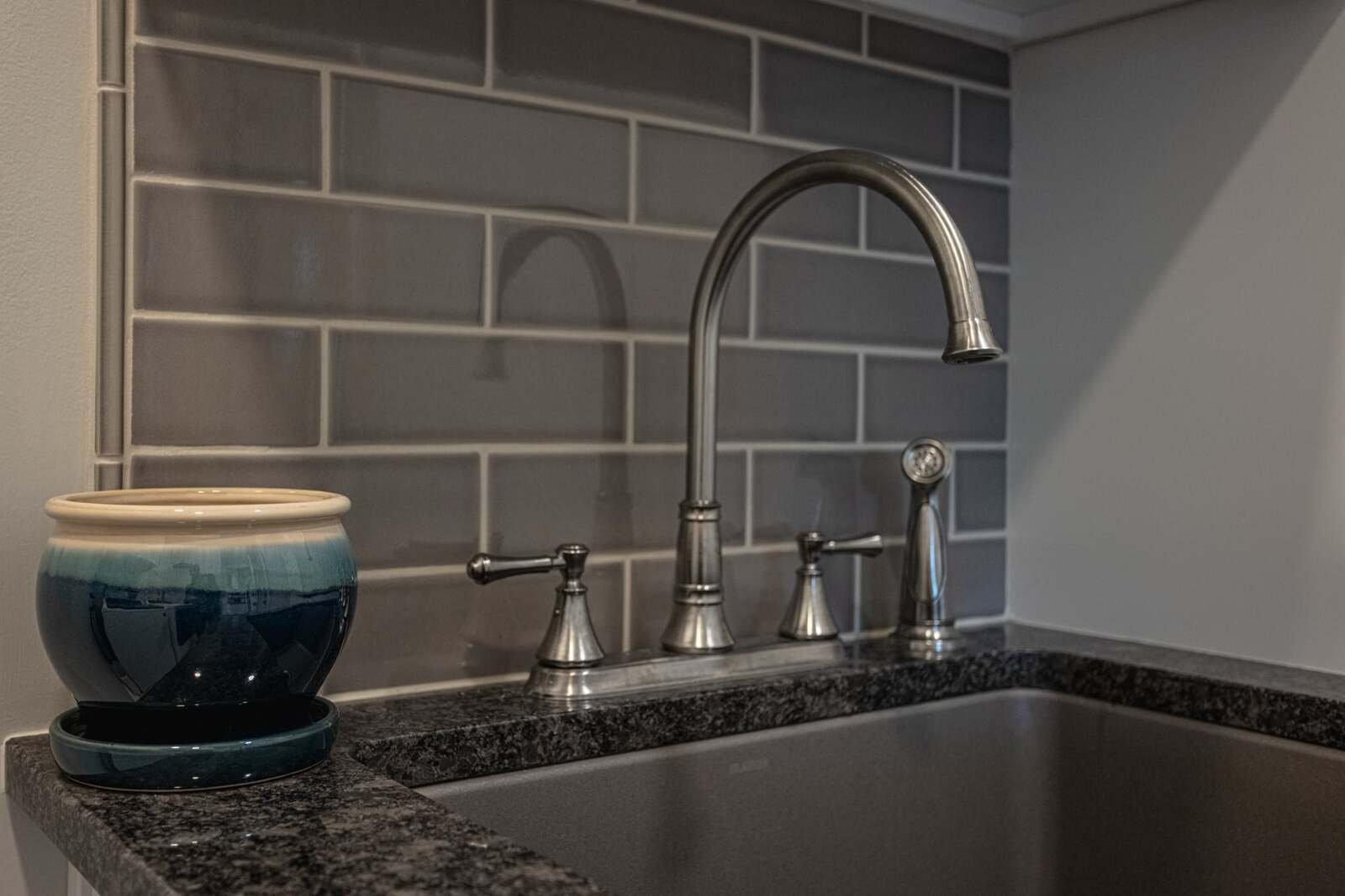 Stainless steel sink faucet with gray tile backsplash