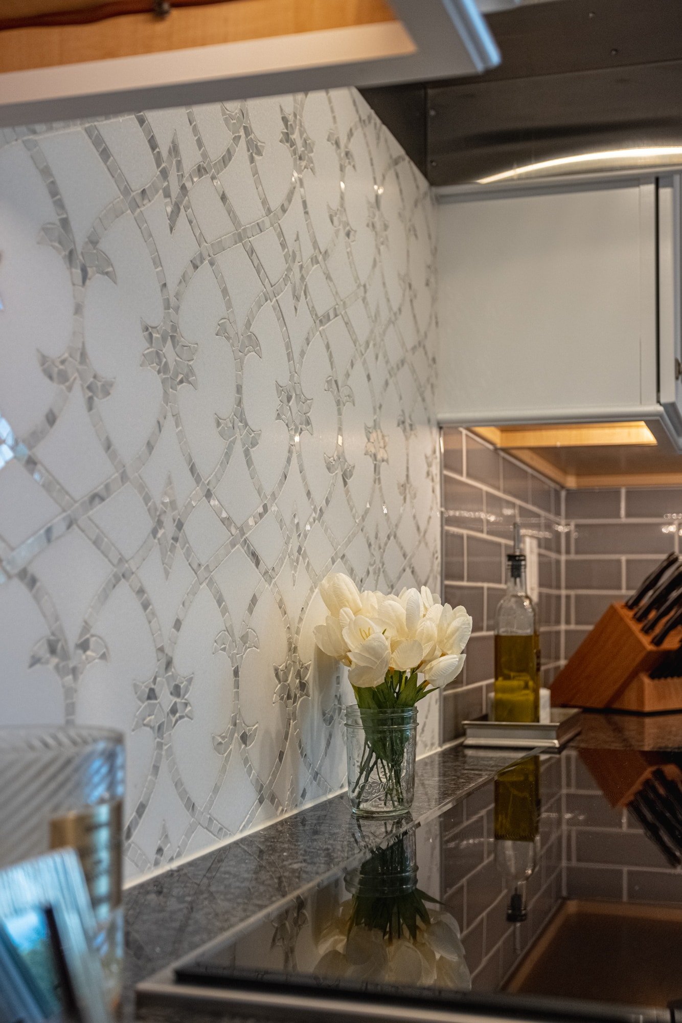 White mosaic backsplash behind range hood with chrome accents 