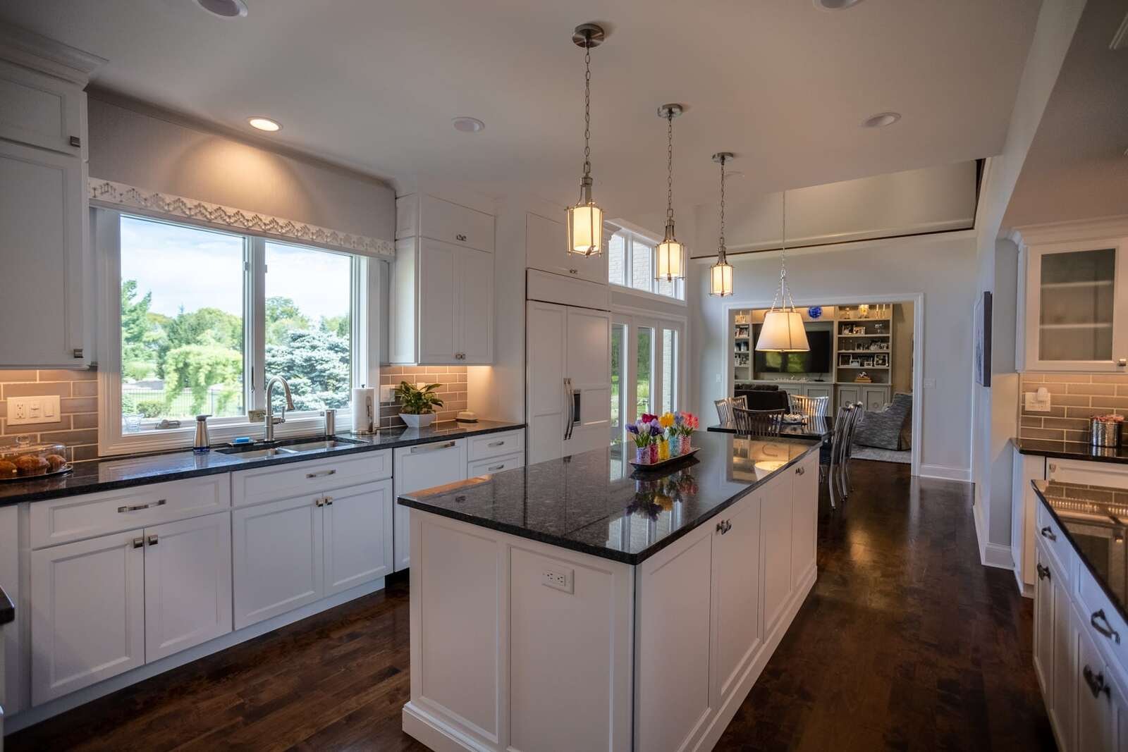 Open concept kitchen design with custom island and storage beneath three light fixtures