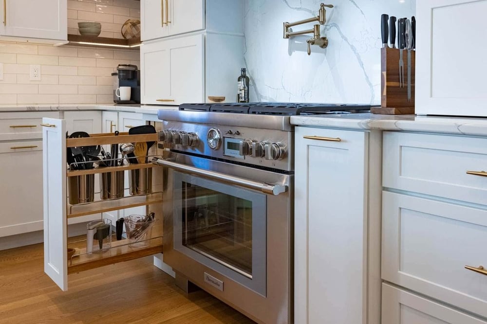 Custom pull out kitchen cabinet with kitchen tools next to kitchen range