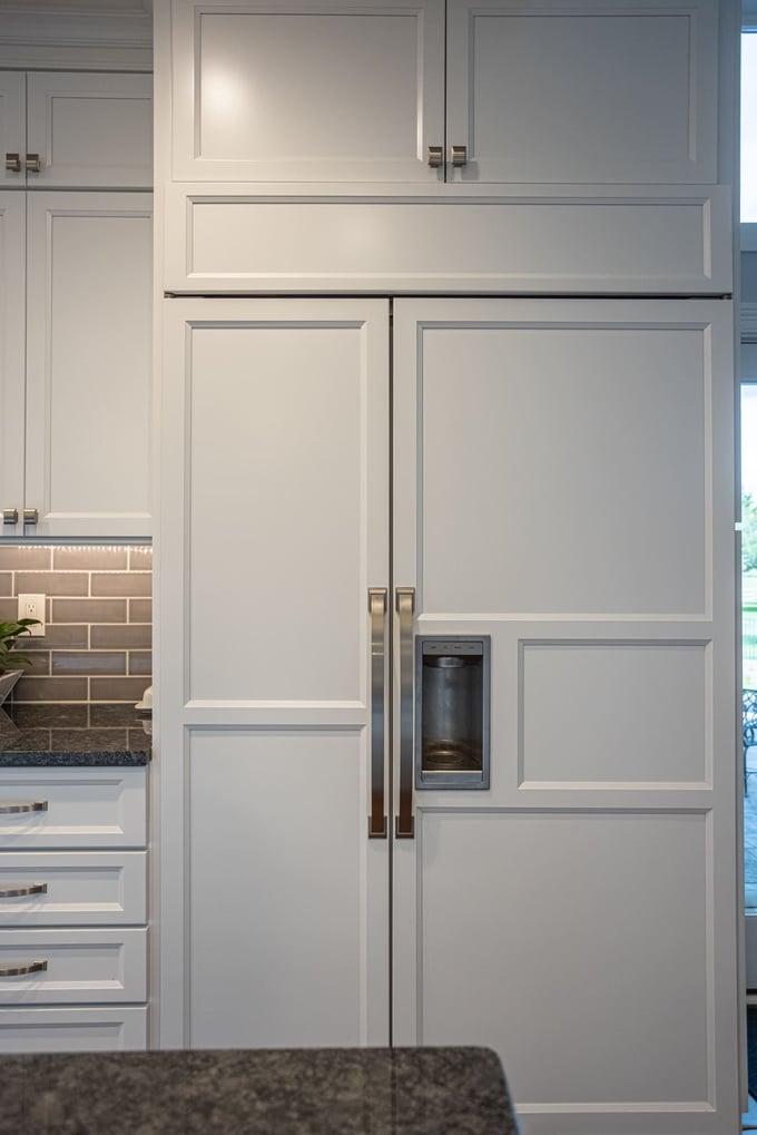 Custom white cabinetry panels on refrigerator with storage above