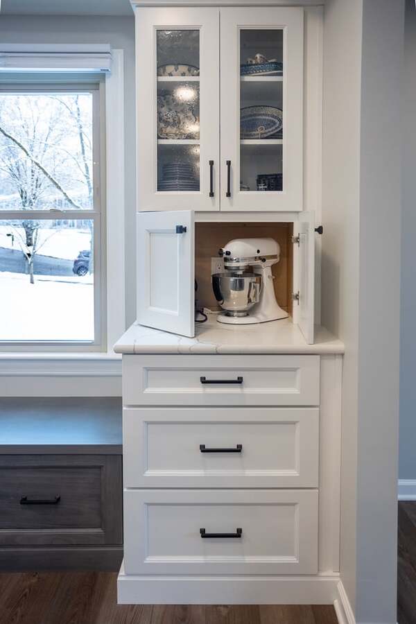 Floor-to-ceiling white kitchen cabinet with glass door paneling on top