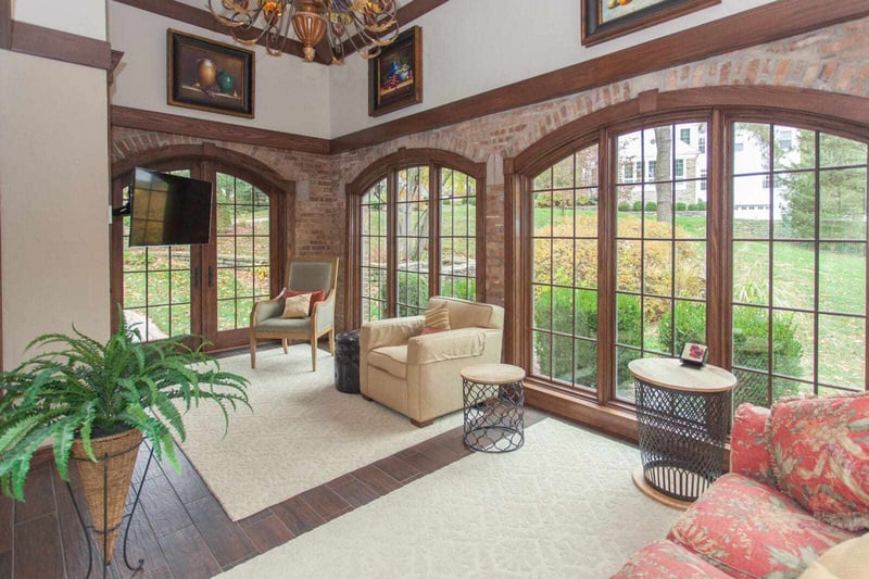 Sunroom addition interior with arched windows and chandelier