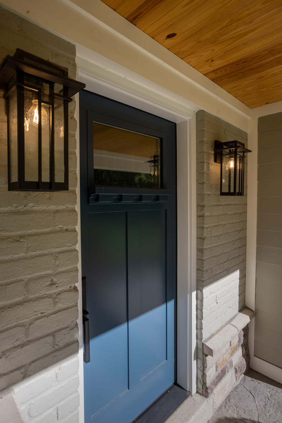 Front blue door and light gray painted brick siding on exterior remodel