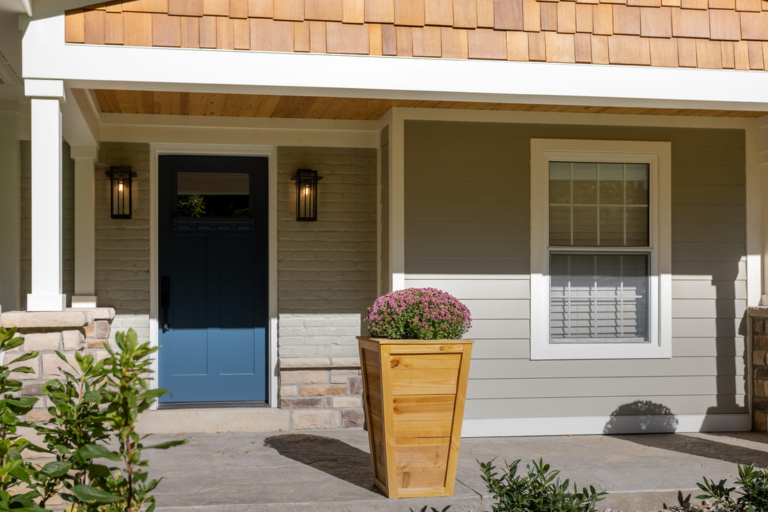 Front porch addition with cedar shake gabled roof and painted gray brick