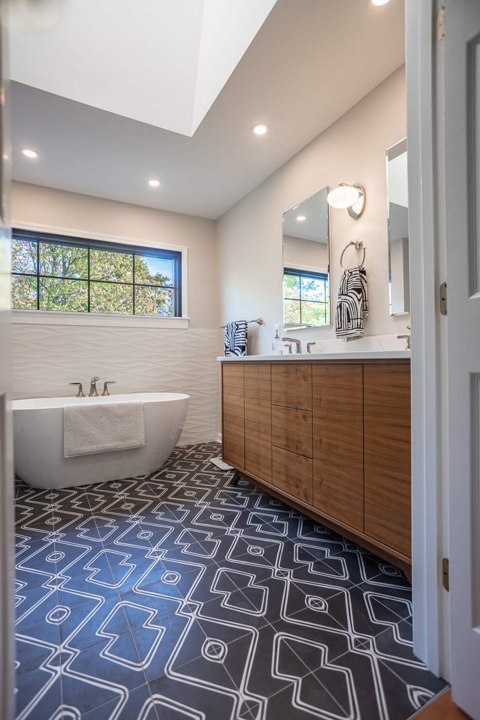 elegant Cincinnati bathroom featuring bathtub double vanity and patterned black and white floor