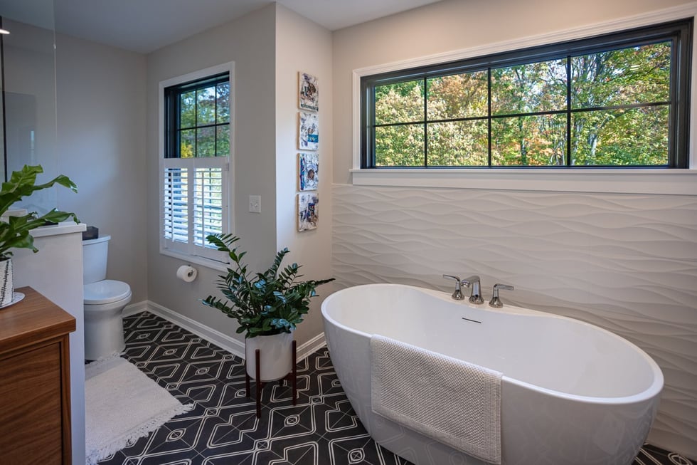 stylish Cincinnati bathroom featuring freestanding bathtub plants and large window with view of trees