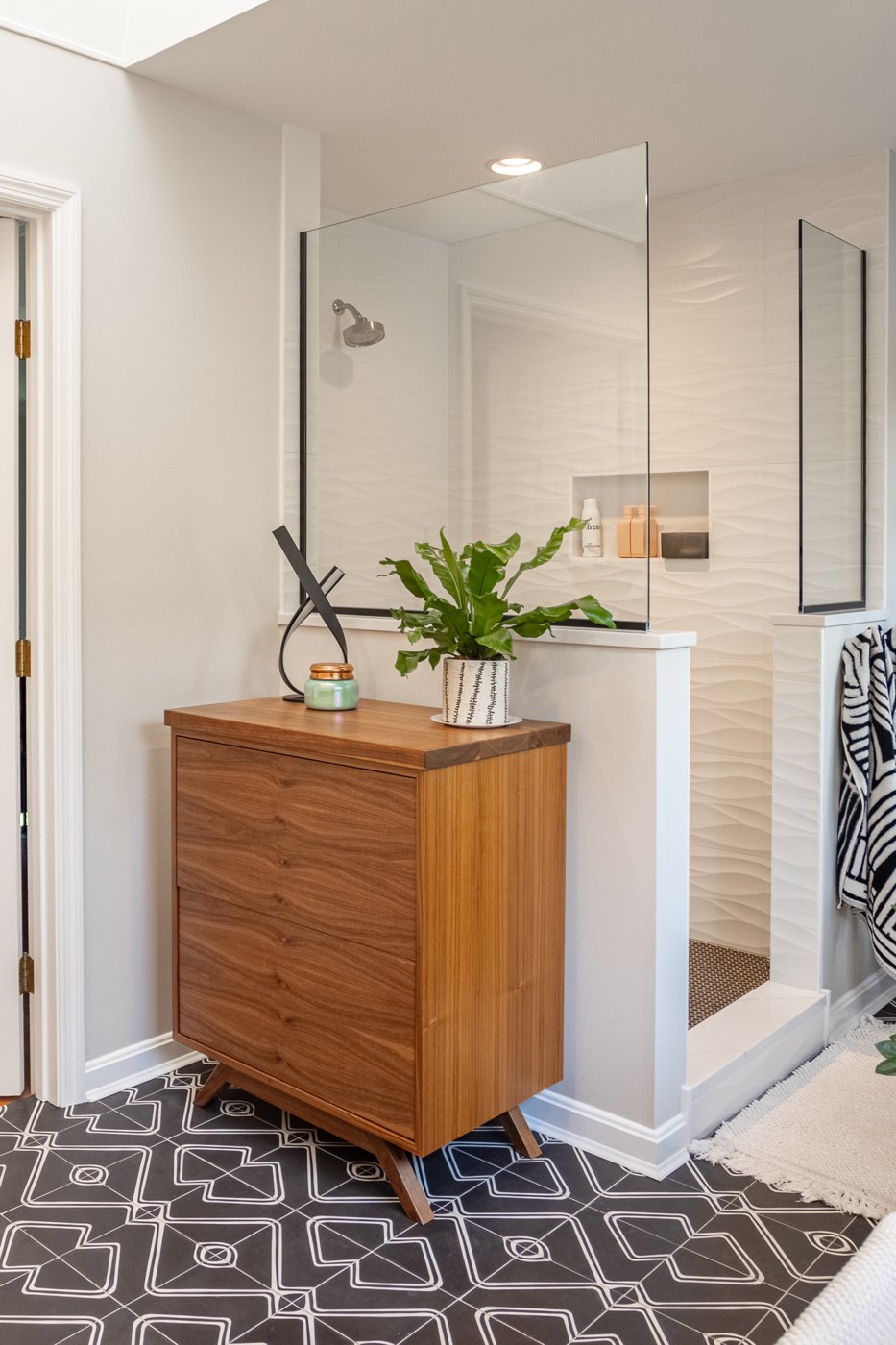 stylish Cincinnati bathroom with wooden vanity potted plant and glass shower enclosure