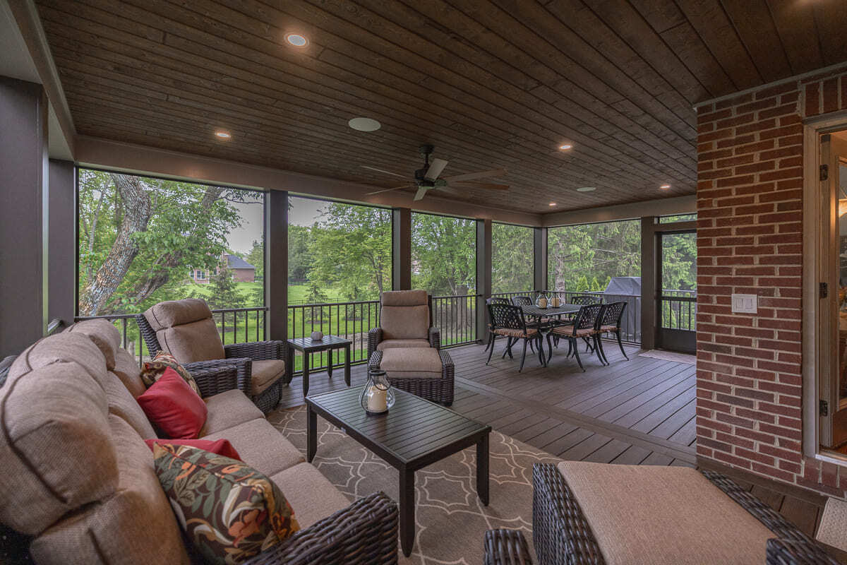 Spacious screened deck with outdoor lounge, dining table, wood flooring, and backyard views.