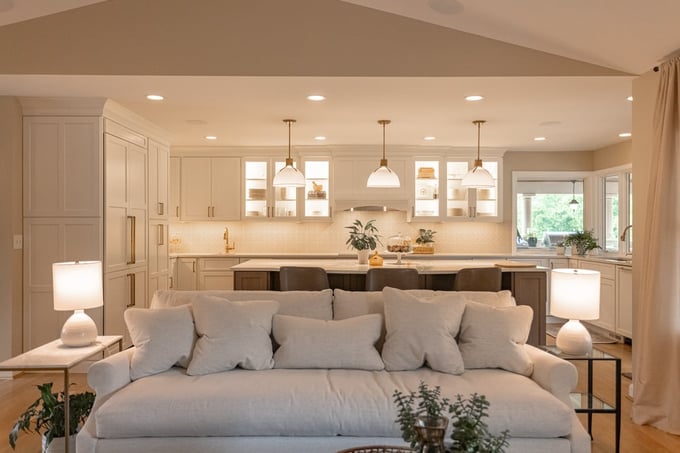 U shaped kitchen with island, pendant lighting, and creamy colors seen from the living room by Legacy Builders Group in Cinncinati