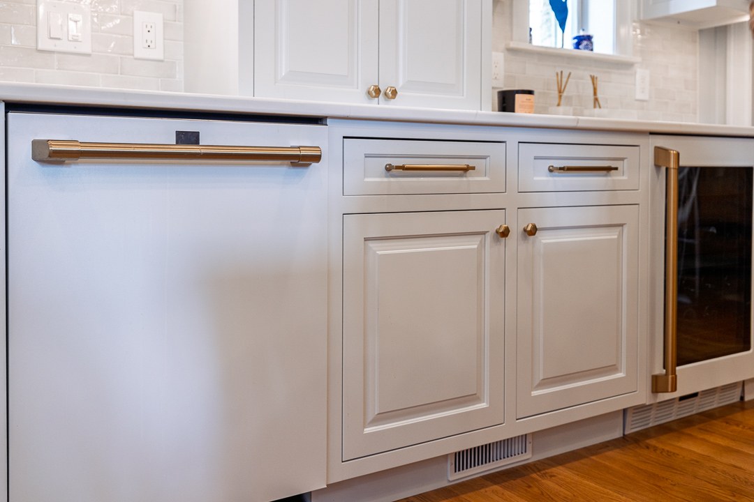 Cincinnati kitchen detail with white cabinetry, brass hardware, integrated dishwasher panel, and hardwood flooring