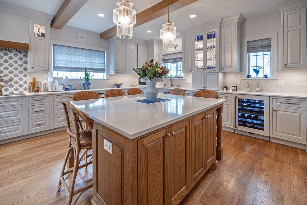 Cincinnati kitchen with large wood island, white cabinetry, woven stools, pendant lighting, and built-in wine fridge in a bright open space