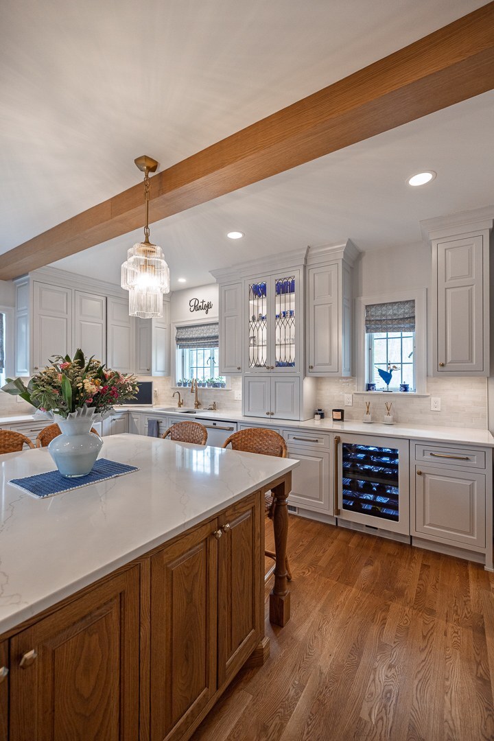 Cincinnati kitchen with white cabinetry, wood island, pendant lighting, built-in wine fridge, and warm hardwood floors