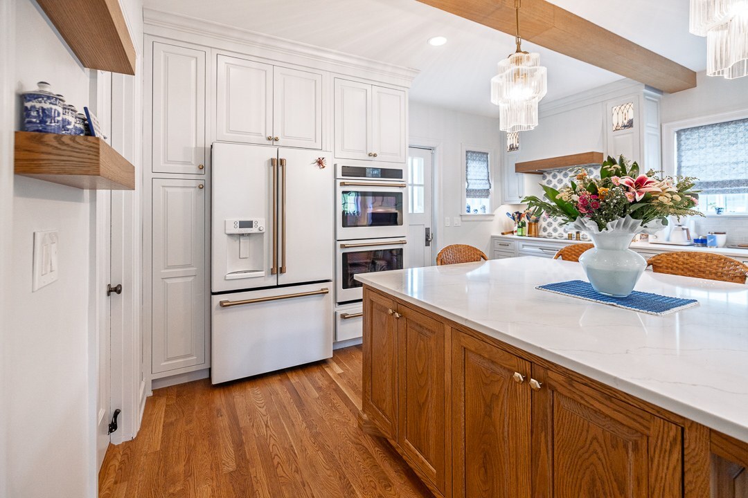 Cincinnati kitchen with white cabinetry, wood island, pendant lighting, stainless appliances, and warm hardwood floors in a bright space