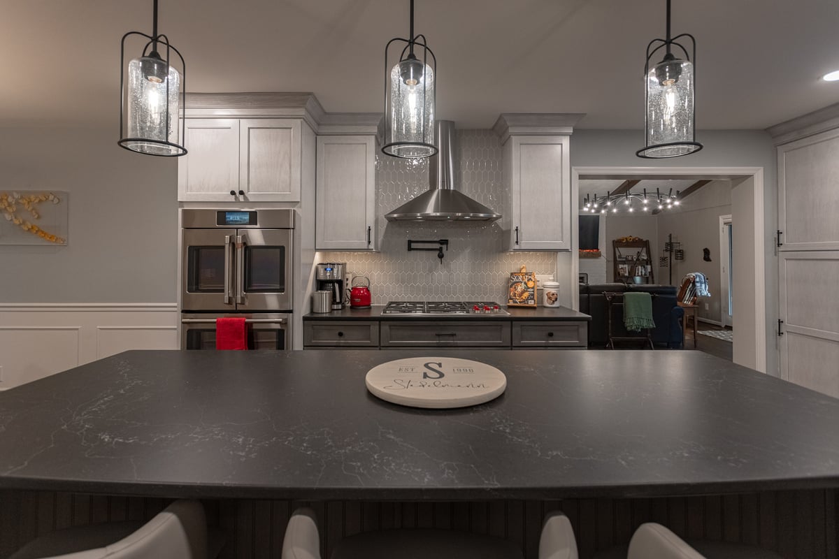 Black countertop, chrome range hood, elongaated hexagonal backsplash in Montgomery kitchen remodel by Legacy Builders Group