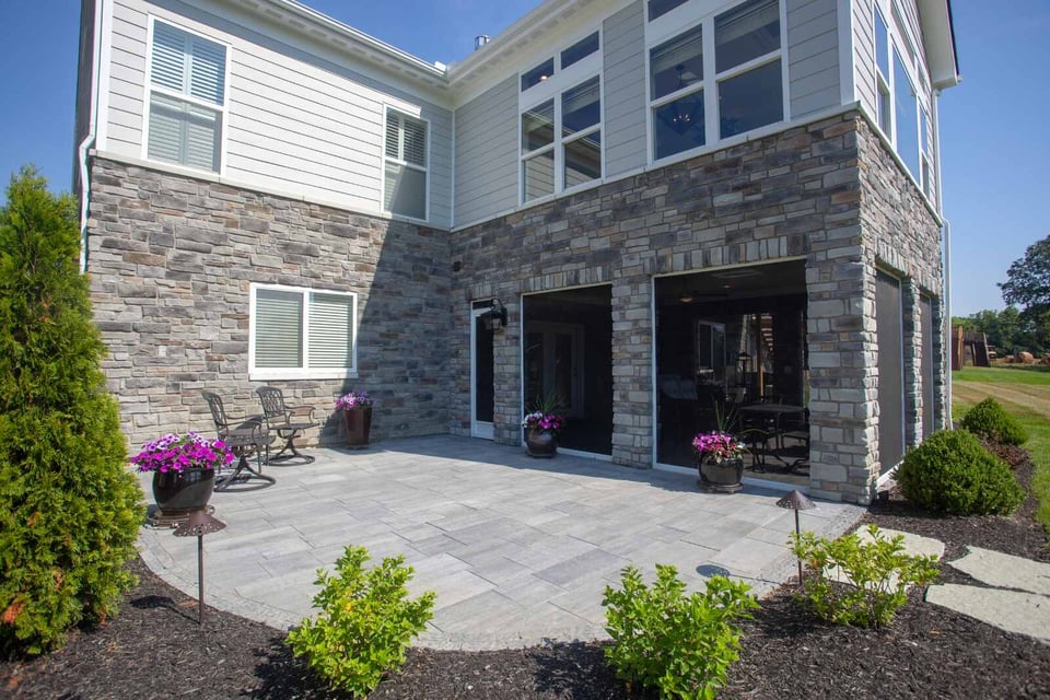 Stone patio with seating and planters behind a modern home with large windows in Cincinnati, OH