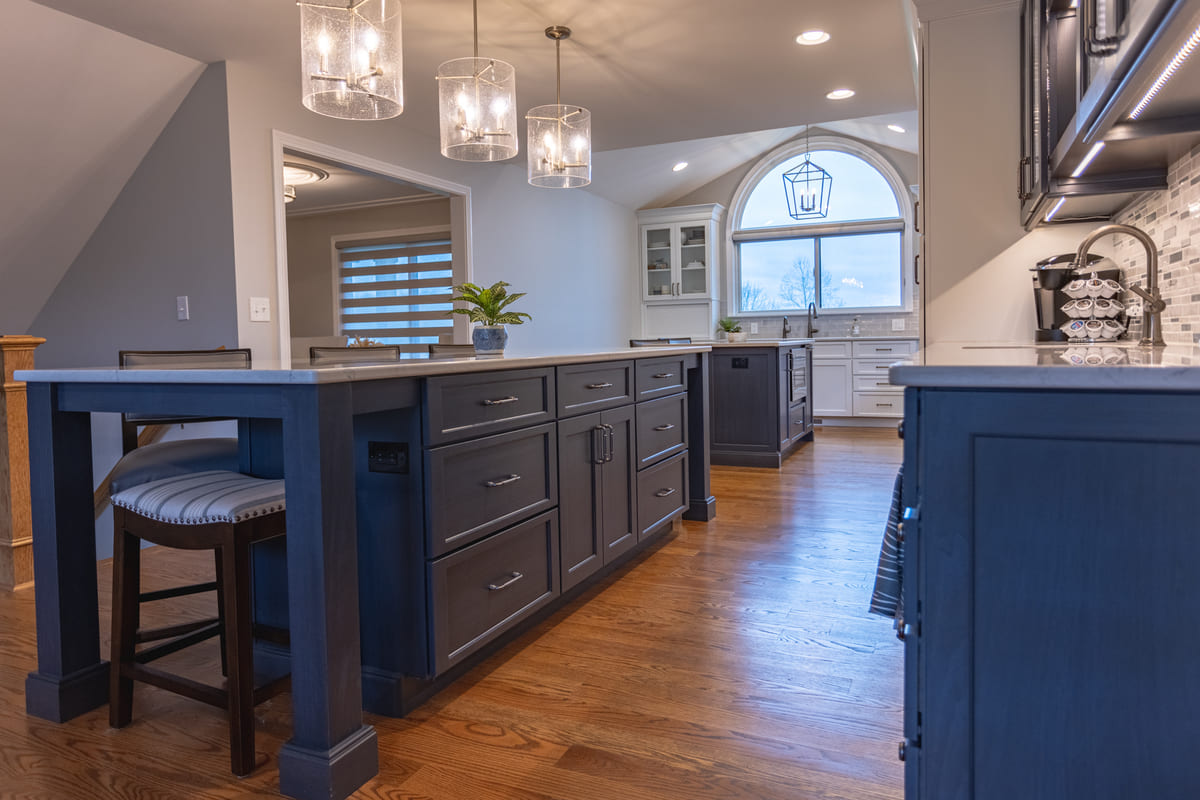 Blue kitchen island with seating and storage beneath three pendant light fixtures in Cincinnati kitchen remodel