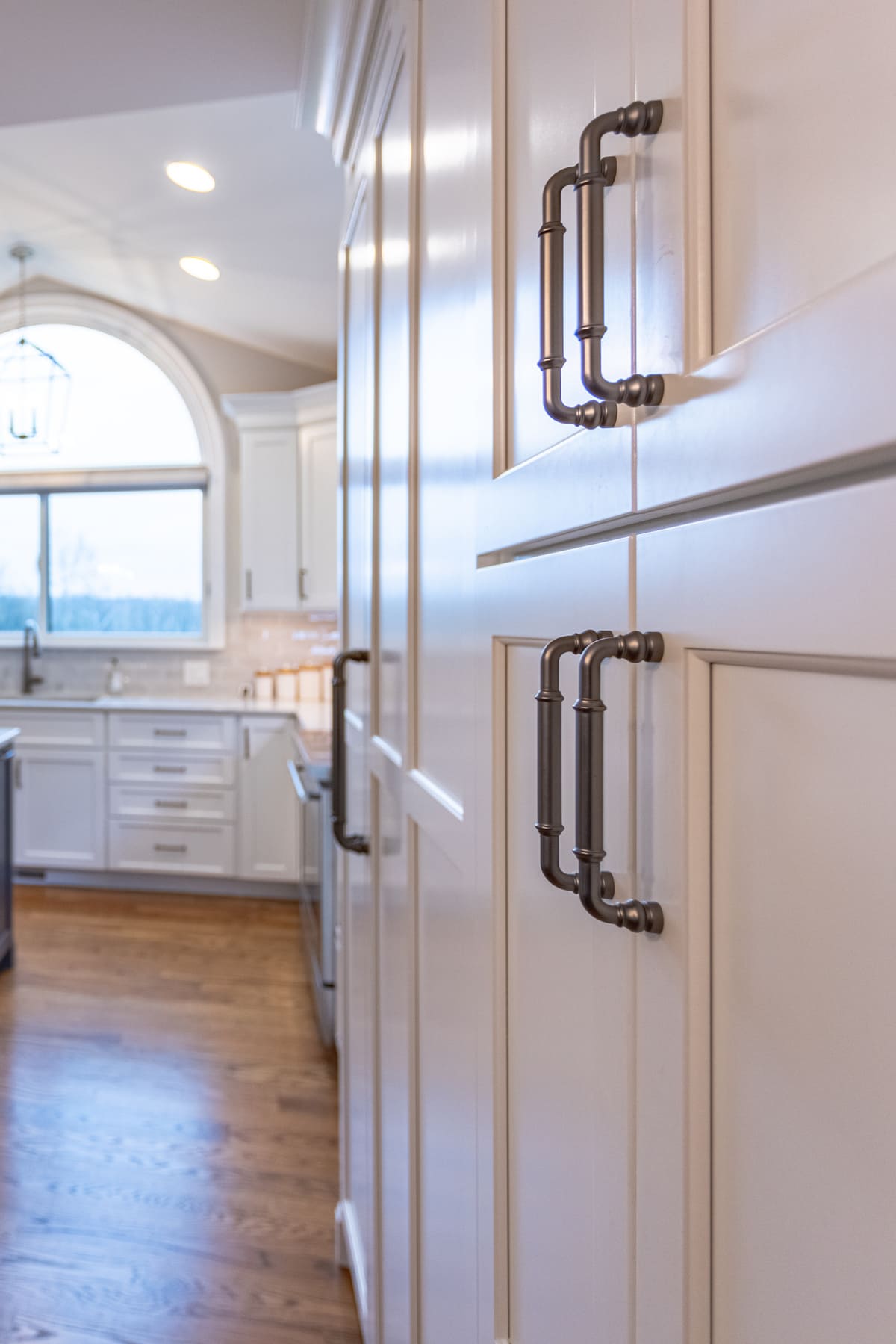 Up-close shot of D-shaped cabinet pulls on white shaker cabinets with natural light coming in from window in Butler County, OH kitchen remodel