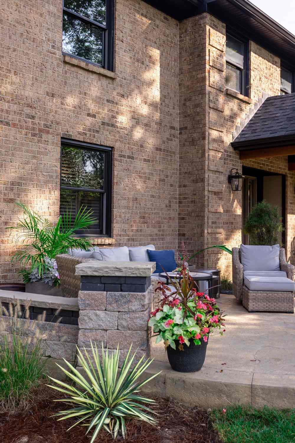 Concrete patio with stacked stone seating wall and plants
