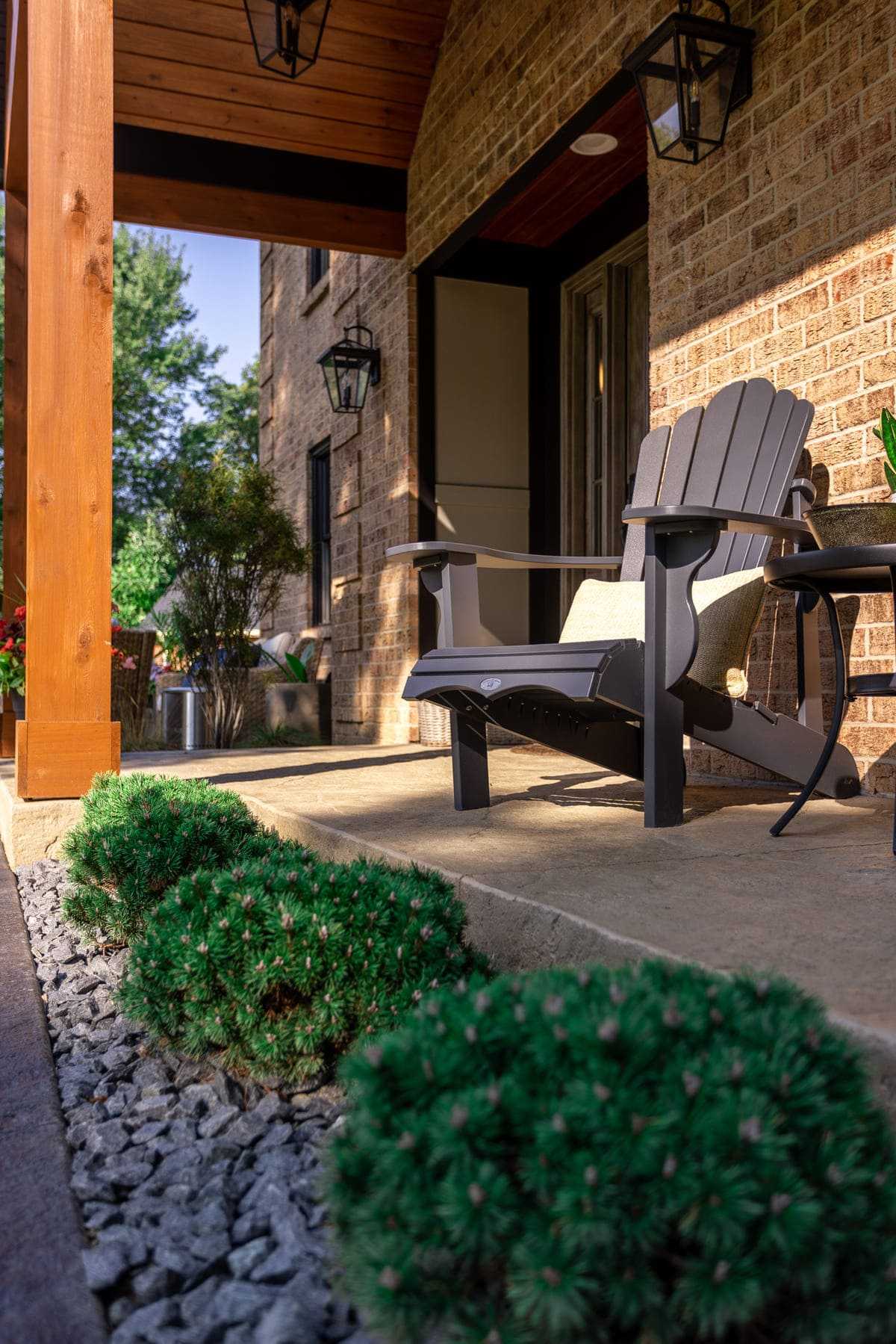 Covered porch attached to brick home with Adirondack chair