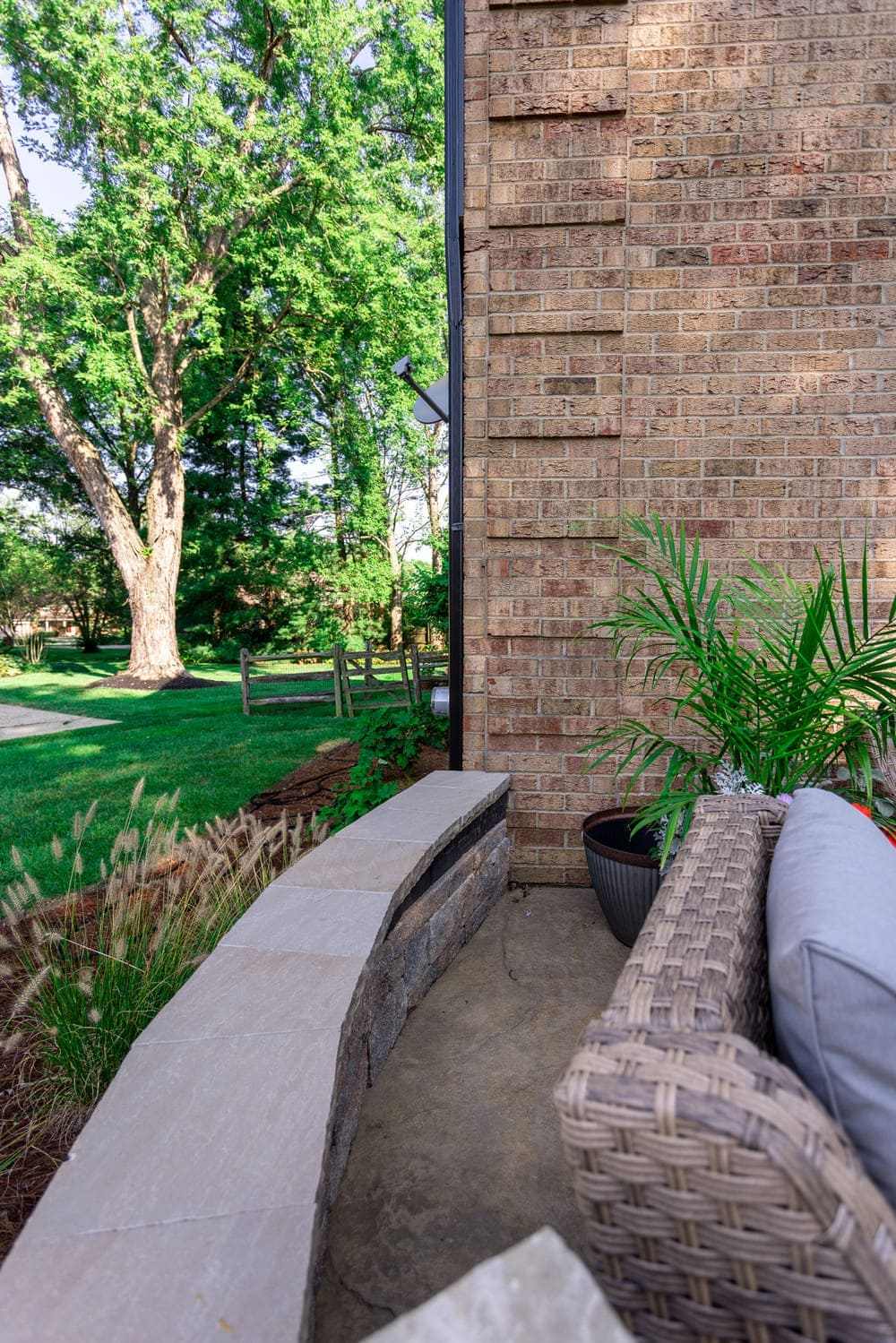 Curved stone seating wall on concrete patio with furniture