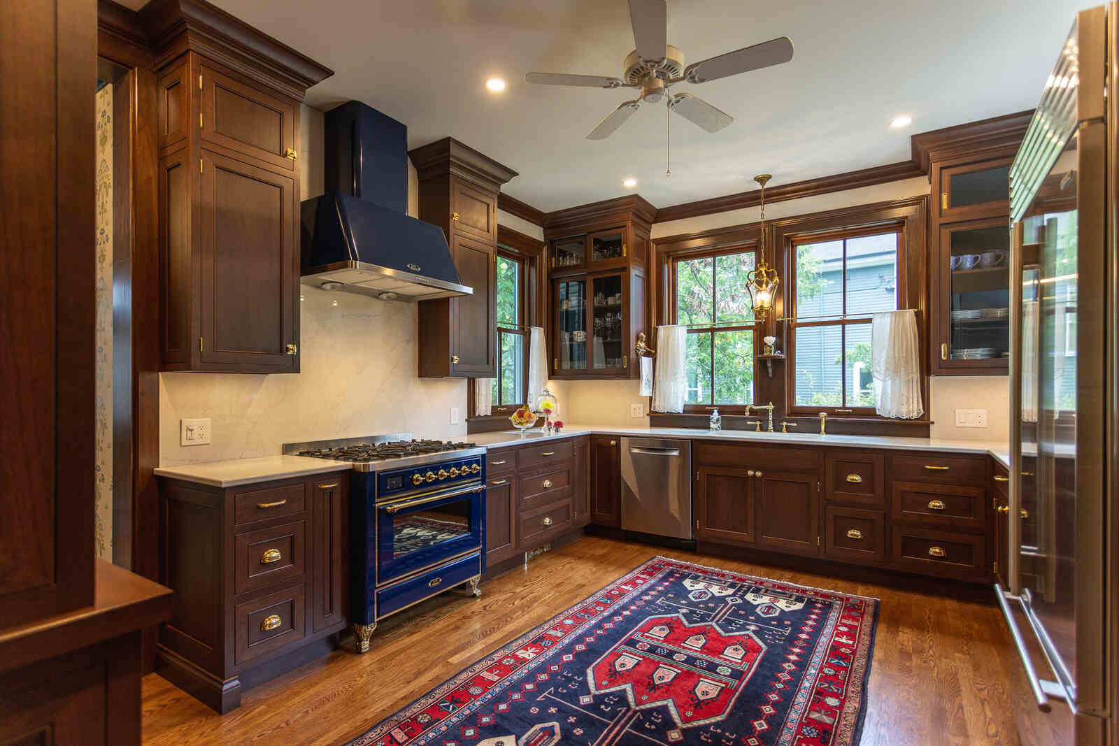 mahogeny cabinets with dark blue professional stove and range hood kitchen