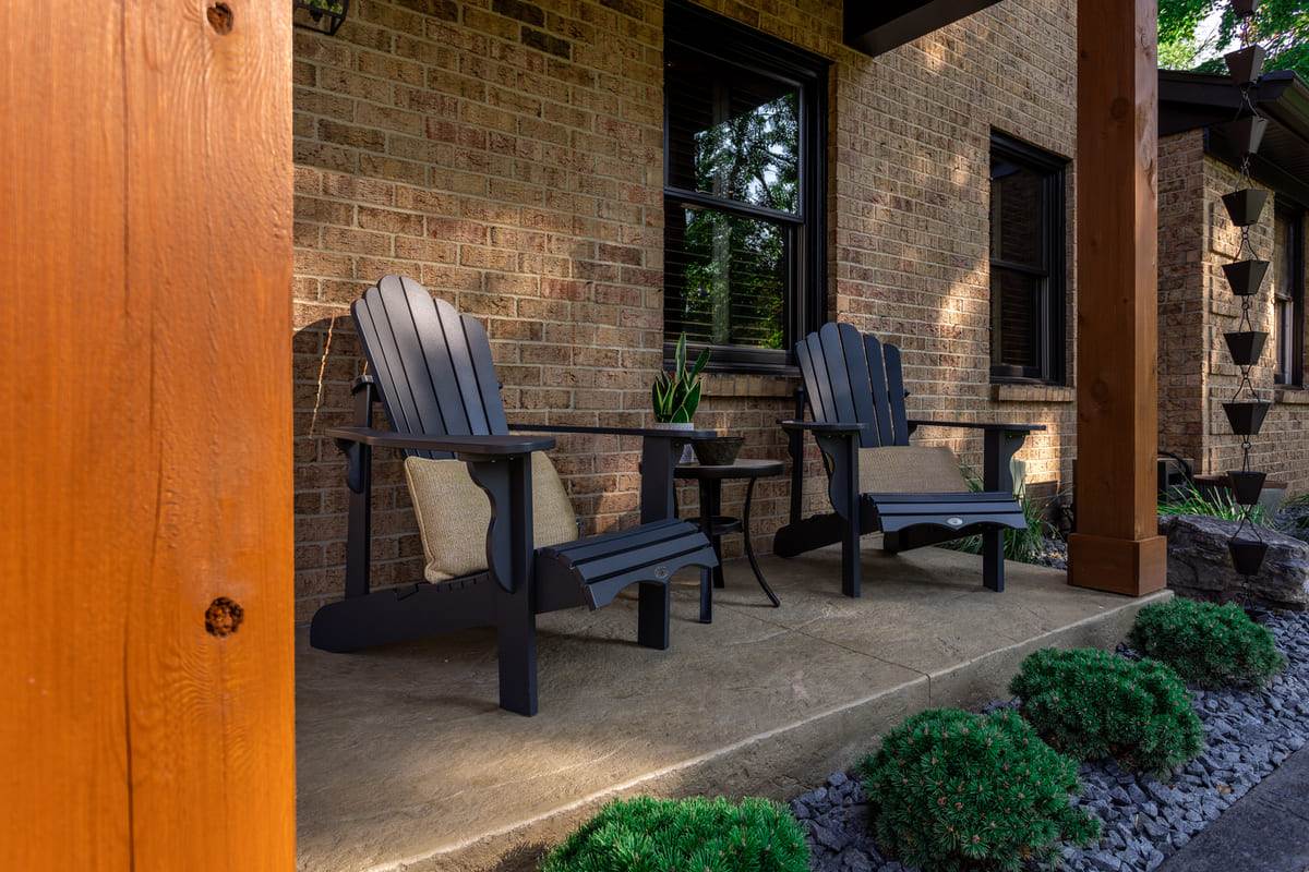 Two Adirondack chairs on front porch with view of cedar post