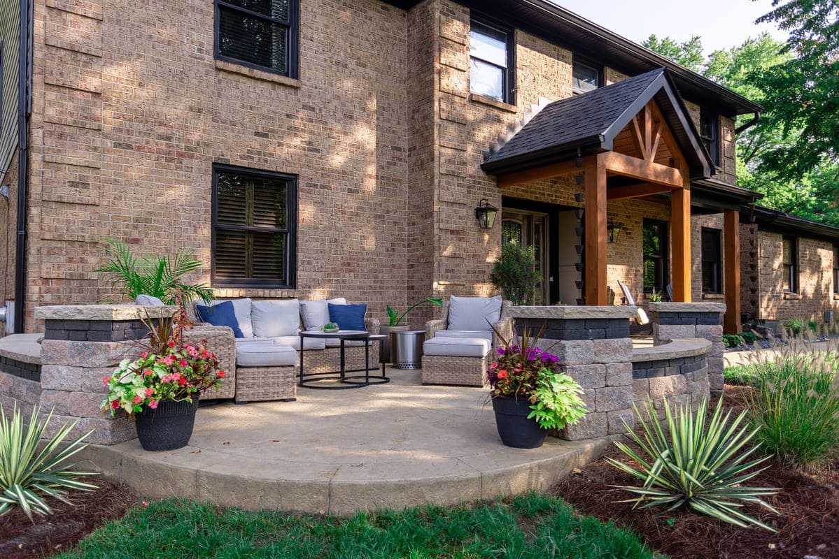 View of round concrete patio with curved seating wall and patio furniture