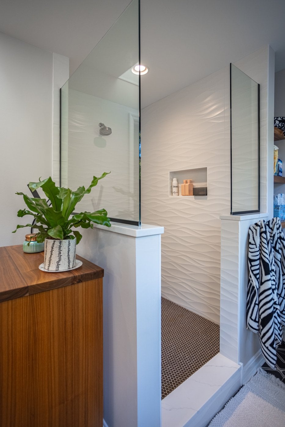 Cincinnati shower with white textured walls and glass divider next to wooden cabinet Cincinnati shower with white textured walls and glass divider next to wooden cabinet