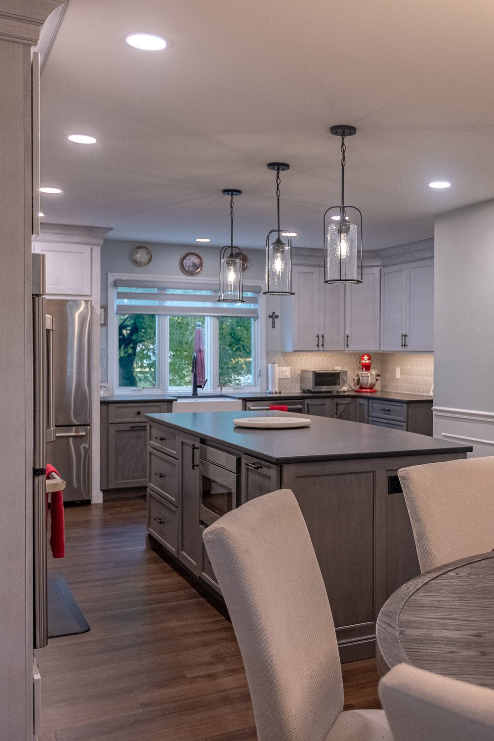 Modern kitchen in Greater Cincinnati featuring gray cabinets, a large island, pendant lights, and stainless steel appliances in a cozy, open-concept design