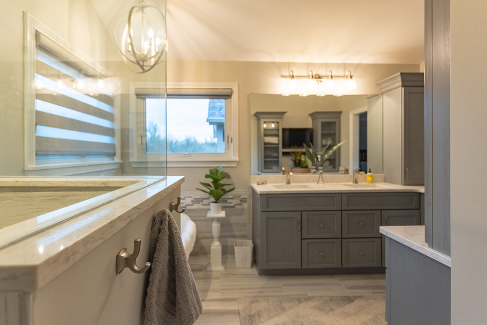 Wide view of master bathroom in Cincinnati featuring pendant light, soaker tub, double vanity and walk-in shower